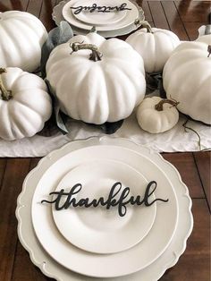 white pumpkins and plates with the word grateful written in cursive writing on them