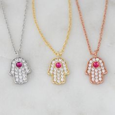 "The Hamsa is said to bring its owner happiness, luck, health, and good fortune. Basically, you NEED this in your life! Super cute Hamsa featuring a ruby stone. Very dainty and delicate, perfect for stacking or wearing it on its on for protection. - - - D E T A I L S - - - * Made of 925 Sterling Silver * THICK plating of 14k Gold, Rose Gold or Rhodium * Hamsa charm measures 11mm x 8mm * Chain Measures 16\" + 3\" Extension Chain * Made of highest grade CZs for an authentic diamond look Made with Spiritual Good Luck Necklace With Round Shape, Good Luck Spiritual Necklace With Round Shape, Spiritual Round Good Luck Necklaces, Spiritual Good Luck Round Necklace, Good Luck Charms Pendant Necklace, Crystal Charm Pendant Necklace For Gift, Crystal Pendant Necklace With Charms As A Gift, Good Luck Gemstone Round Pendant Necklace, Pendant Crystal Necklace With Charms For Gift