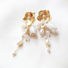 Make a statement on your special day with our gorgeous CALLIE Freshwater Pearl Floral Earrings! Perfect for any modern bride, they combine golden tones with glimmering pearl accents to create an exquisite flowery design. A must-have accessory to complete your look! - PLEASE ALLOW APPROX 10 BUSINESS DAYS FOR COMPLETION BEFORE SHIPPING. - Handcrafted with genuine freshwater pearls and Austrian crystals- Created in my studio in PA- White opal crystals- Freshwater pearls- Polymer clay flowers - Yell Gold Elegant Flower Earrings With 3d Flowers, Gold Plated Flower Charm Earrings For Wedding, Elegant Gold Flower Earrings With 3d Details, Dainty Gold Jewelry With 3d Flowers, Graceful Yellow Gold Wedding Earrings, Delicate Gold Pearl Chandelier Earrings, Gold Pearl Chandelier Earrings Delicate Style, Gold Pearl Chandelier Earrings In Delicate Style, Delicate White Gold Plated Pearl Earrings