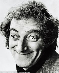 an old black and white photo of a man with curly hair smiling at the camera