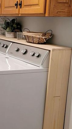 a washer and dryer in a small room with wooden cabinets on the wall