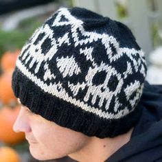 a young man wearing a black and white knitted hat with an animal motif on it