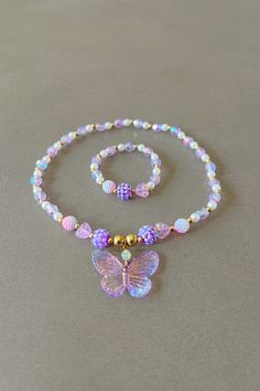 a necklace and bracelet with a butterfly on the bead is sitting on a table