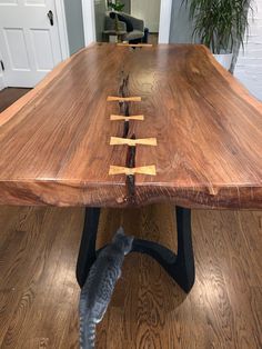 a cat is standing on the floor looking at a table that has been made out of wood