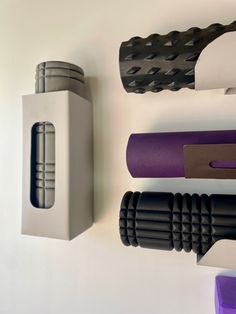 several yoga mats are lined up on the wall next to each other, including one purple and one black