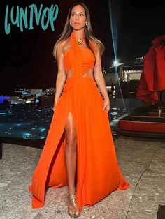 a woman in an orange dress posing for the camera with her legs slited up