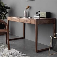 a wooden desk sitting next to a chair in front of a wall with pictures on it