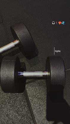 two black dumbbells sitting on top of each other in front of a wall