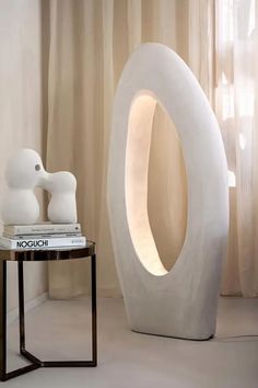 a white sculpture sitting on top of a table next to a book and a vase