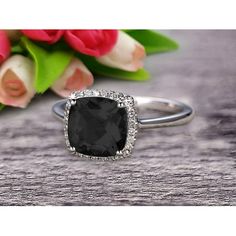 a black diamond ring sitting on top of a table next to pink flowers and tulips