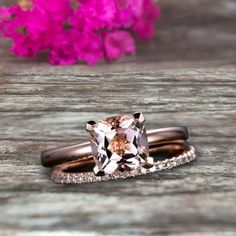 two wedding bands with an engagement ring set in rose gold and white diamonds, on top of a wooden table