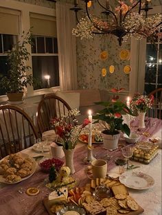 a dining room table is set with food and candles in the center, along with flowers