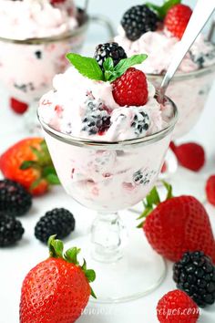 two glasses filled with ice cream and berries on top of each other next to some strawberries