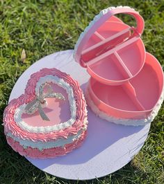 a cake shaped like a heart sitting on top of a white plate in the grass