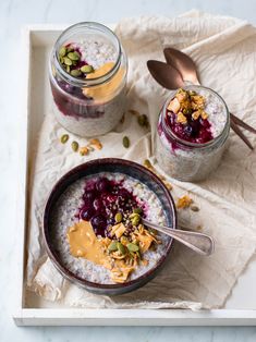 two bowls filled with oatmeal and fruit on top of a white tray