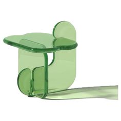 a green plastic chair sitting on top of a white floor next to a shadow from the ground