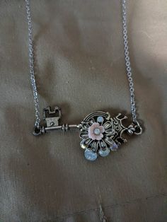 Flowers and opal stones adorn this crown key. Metal Key Pendant Jewelry, Vintage Pendant Jewelry With Keys, Key Pendant Jewelry In Metal, Metal Jewelry With Keys For Gifts, Key Detail Metal Jewelry As A Gift, Silver Key Pendant Jewelry, Vintage Metal Jewelry With Keys Detail, Vintage Metal Jewelry With Keys, Vintage Metal Key Jewelry