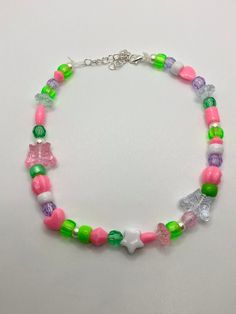 This necklace has assorted beads consisting of different shapes and colors. The theme of this necklace is white, pink, and green. The necklace is 16 inches from the clasp to the last link of the extender. The colors, shapes, and sizes of the beads may vary from the example in the picture but it will be the same style of necklace. Cute Handmade Green Beaded Necklaces, Trendy Pink Beaded Necklaces With Large Beads, Trendy Pink Beaded Chain Necklaces, Trendy Pink Beaded Necklace With Large Beads, Cute White Beaded Chain Necklace, Trendy Pink Necklace With Letter Beads, Trendy Pink Beaded Necklaces With Heart Beads, Cute Pink Heart Beaded Necklaces, Pink Beaded Necklaces With Lobster Clasp