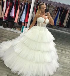 a woman is taking a selfie in a white wedding dress with tiered layers