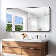 a bathroom vanity with a large mirror above it and flowers in the vase on the sink