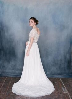 a woman in a white wedding dress standing on a wooden floor next to a blue wall