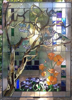 a stained glass window with flowers and trees in the background on display at a park