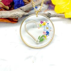 a glass pendant with flowers in the shape of a heart