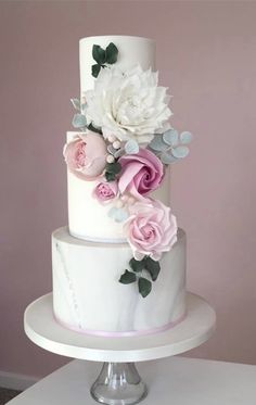 a three tiered cake with pink and white flowers