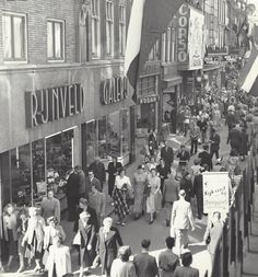 a crowd of people walking down a street next to tall buildings