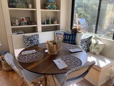 a dining room table with blue and white plates on it, next to a window