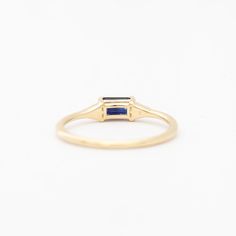 A azure blue sapphire set in Jennie Kwon's signature deco setting makes for a perfectly balanced piece that's deliciously dainty. Wear her as an alternative bridal ring—or on any finger, just because. Made in the U.S.A. 14 karat gold set with one 5 mm x 3 mm blue sapphire and two 1.2 mm diamonds. Fine Jewelry Sapphire Ring, Emerald Cut, May Birthstone, Sapphire Emerald-cut Birthstone Ring In Fine Jewelry Style, Modern Emerald-cut Sapphire Ring With Polished Finish, Gold Emerald-cut Sapphire Ring With Gemstone Accents, 14k Gold Emerald-cut Sapphire Ring With Center Stone, Jennie Kwon, Alternative Bridal, Azure Blue, Emerald Cut