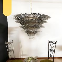 a chandelier hanging from the ceiling over a dining room table with two chairs