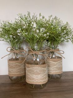 three mason jars with twine and flowers in them