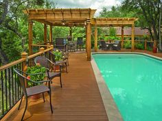 an empty swimming pool in the middle of a wooded area with chairs and tables around it