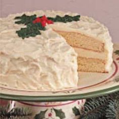 a cake with white frosting and holly decorations on it sitting on a platter