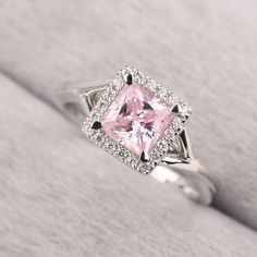 a pink diamond surrounded by white diamonds in a silver ring on top of a blanket