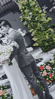 a bride and groom standing in front of flowers