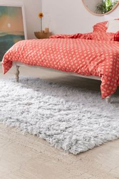 a bed sitting on top of a wooden floor next to a white and gray rug