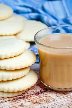 some cookies and a glass of milk on a wooden table with a blue towel in the background