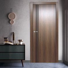 a wooden door in a room next to a chest of drawers and a lamp on the wall