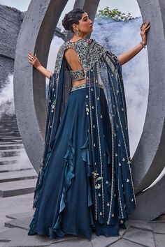 Blue panelled cape with floral embroidery. Paired with attached cancan lehenga and embroidered padded corset blouse.
Components: 3
Pattern: Embroidered
Type Of Work: Floral
Neckline: V neck
Sleeve Type: Cape sleeves
Fabric: Georgette, viscose satin organza  
Color: Blue
Other Details: 
Tassel detailing
Criss cross detailing
Lehenga length: 45
Occasion: Wedding - Aza Fashions Draped Lehenga, Drape Lehenga, Cancan Lehenga, Corset Blouse, Cape Sleeves, Set Women, Aza Fashion, Sleeve Type, Floral Embroidery