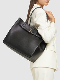 Find TOM FORD Audrey Grain Leather Tote Bag on Editorialist. The TOM FORD Audrey Grain Leather Tote Bag features a buckle closure, top handles, and one internal zip pocket. The bag measures 29cm in height, 33cm in width, and 18cm in depth. The handle drop is 27cm. The bag also features logo details. Tom Ford Leather, Tom Ford Bag, Buckle Bags, Black Leather Tote Bag, Ski Accessories, Zip Tote, Medium Tote, Womens Toms, In Depth