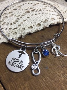 Medical assistant graduation Gift for medical assistant personalized bracelet, MA charm bracelet, birthstone bracelet, silver initial charm  Beautiful silver personalized medical assistant charm bracelet  Features a hand polished stainless steel laser etched charm, detailed Stethoscope charm, and your choice of personalization  *You choose the initial  *You choose the birthstone  High quality bracelet band resists tarnishing and corroding  Expandable band Fits adult 6-8' wrists sizes  Makes a thoughtful and long lasting gift for any special medical assistant  Please visit my shop for more RN, CNA, Medical assistant necklaces and bracelets ! www.Luxedesignsbysarah.etsy.com Nickel-free Adjustable Surgical Steel Jewelry, Adjustable Nickel-free Surgical Steel Jewelry, Customizable Silver Charm Bracelet, Hypoallergenic Adjustable Surgical Steel Jewelry, Adjustable Hypoallergenic Surgical Steel Jewelry, Adjustable Silver Surgical Steel Jewelry, Personalized Silver Stainless Steel Charm Bracelet, Silver Stainless Steel Charm Bracelet For Personalized Gift, Adjustable Silver Jewelry For Graduation Gift