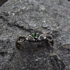 This unique silver engagement ring features a stunning design with twin snakes wrapping around each other, facing each other, and holding a sparkling emerald between their heads. The intricate detailing of the snakes' scales and the vivid green of the emerald make this ring a truly eye-catching piece of jewelry.  Characteristics: Metal - Recycled solid sterling silver  Stone - Cubic Zirconia Finish - Oxidized. View all silver gothic rings: https://www.etsy.com/shop/TinyShinyJewel?ref=seller-platform-mcnav&section_id=42765371 Care instructions: To care for the ring, avoid contact with water and chemicals such as perfumes and lotions. When the ring is not in use, store it in a dry, cool place to prevent tarnishing. Additional information:  ✦ All rings are made to order. An average turnaround Silver Fantasy Rings For Collectors, Fantasy Sterling Silver Ring, Sterling Silver Fantasy Rings As Gift, Magical Sterling Silver Crystal Ring For Gift, Mystical Green Gemstone Jewelry, Silver Fantasy Promise Ring, Sterling Silver Fantasy Style Promise Ring, Handmade Magical Silver Rings, Adjustable Silver Magical Style Rings