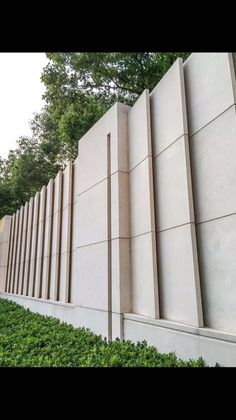 a concrete wall is lined with green bushes