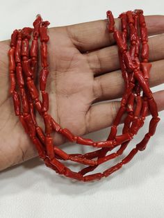 a hand is holding some red plastic beads