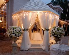 an image of a gazebo decorated with white flowers and lights for a wedding ceremony