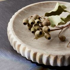 a white plate with some green leaves and berries on it