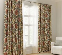 a living room with a white couch and large window covered in floral print curtain panels