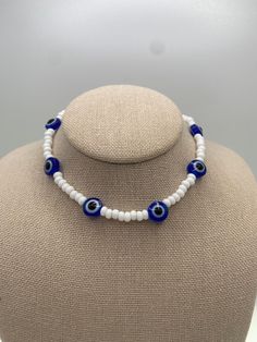 -Blue evil eye beaded necklace with white Czech beads. -This Necklace is simple and yet so fun!  -It's perfect for stacking or wearing alone. It's your choice! -Whether you're going for a casual or a dressy look, this set will add the perfect final touch to all your looks! CARE INSTRUCTIONS TIPS: -Avoid strong chemicals and water to keep them looking like new for much longer -Store away from other jewelry to avoid tangling or scratches -Clean with a soft, dry cloth SHIPPING: -  We are dedicated to ship your orders as soon as a possible.  -Most orders will be shipped out within the same day the order was placed.  -  Feel free to contact us if you need to rush your order, we are happy to accommodate.  -Free shipping on orders over $35 -Feel free to contact us for more details.   ADDITIONAL I Handmade White Evil Eye Bracelet Gift, White Evil Eye Jewelry Gift, White Beaded Round Evil Eye Bracelet, White Evil Eye Bracelet With Round Beads, White Round Beaded Evil Eye Bracelet, Spiritual White Letter Beads, White Evil Eye Bracelet With Colorful Round Beads, Adjustable White Beaded Necklace With Evil Eye, Adjustable White Evil Eye Bracelet With Colorful Beads